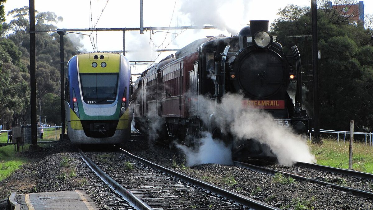A V/Line train passes a steam locomotive at Pakenham station